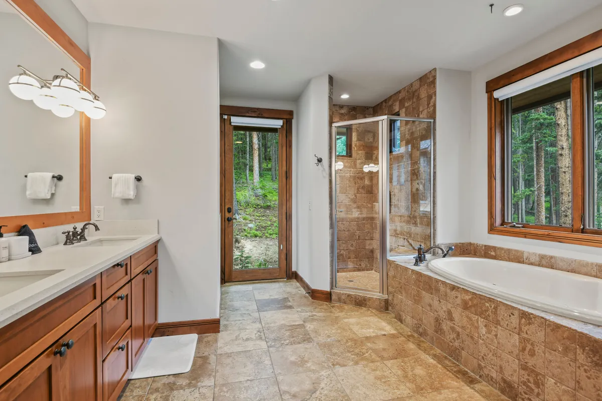 A spa-inspired en suite bathroom with a double-sink vanity, soaking tub, walk-in shower, and large windows that let in natural light. The tranquil design creates a relaxing atmosphere for unwinding after a day in the mountains.